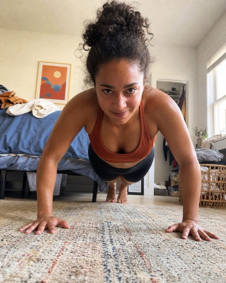 Noa doing her own push-ups in a casual bedroom